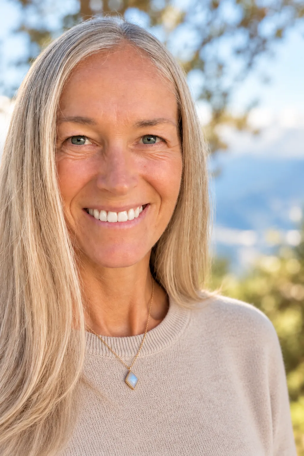 Benita Huterer lächelt in die Kamera, im Hintergrund Bäume und Berge